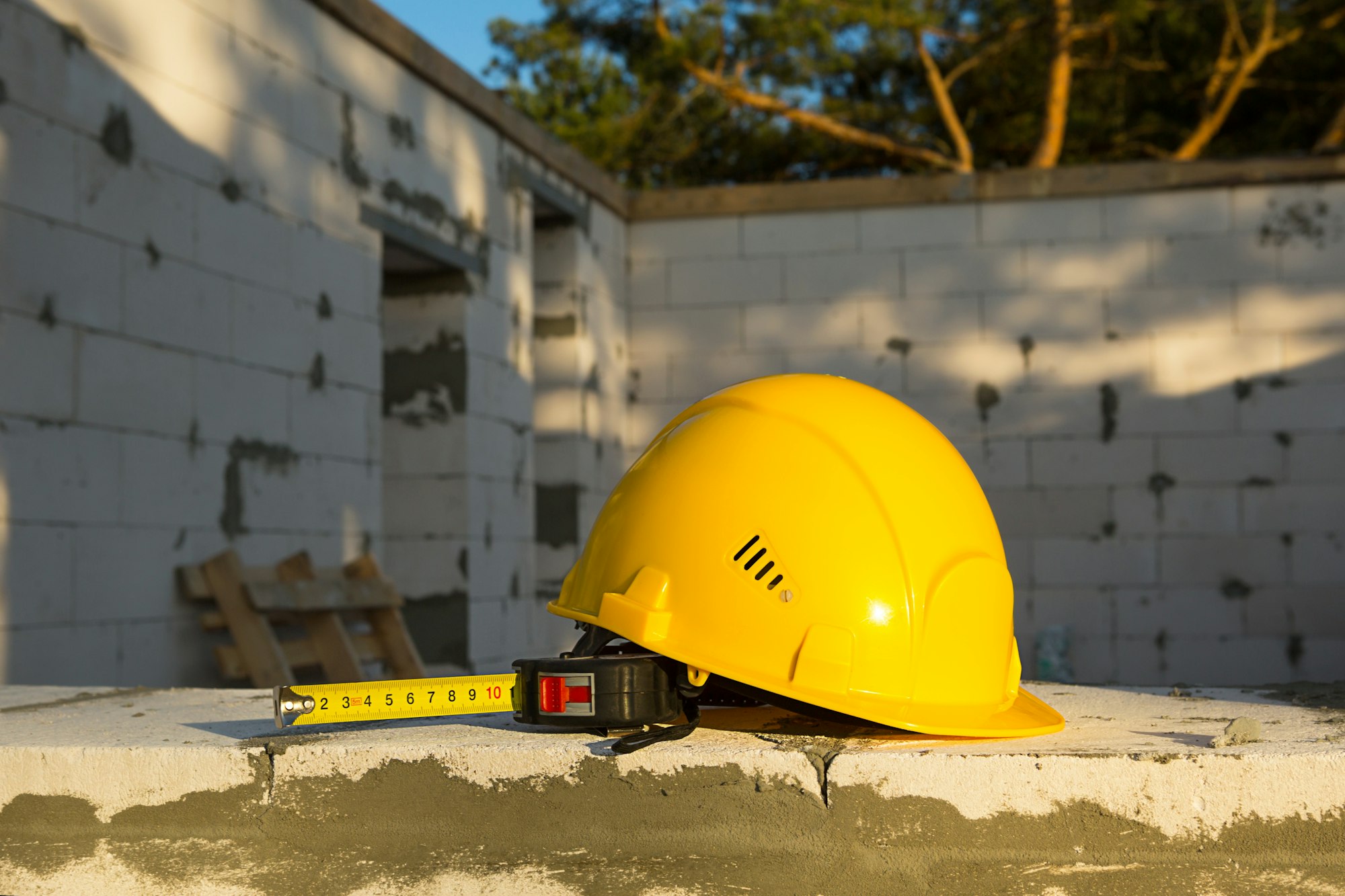 Construction hardhat and measuring tape measure on the window of a house under construction